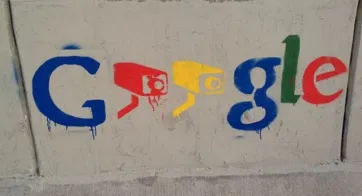 Photo d'un tag sur un mur avec le nom de Google et des caméras de sécurité à la place des O