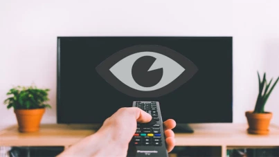Un écran de télé avec la main d'une personne qui pointe la télécommande dessus, un dessin d'oeil est superposé sur la télé pour illustrer le fait que la télé espionne la personne